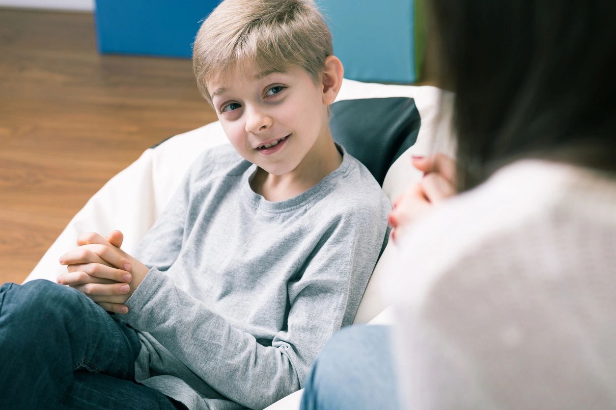 A boy sitting in front of another person.