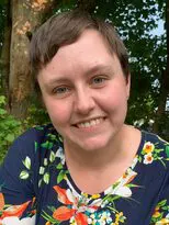 A woman with short hair wearing floral shirt.