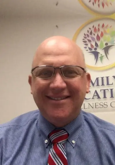 A man with glasses and bald head wearing a tie.