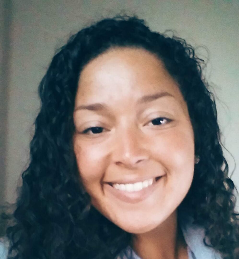 A woman with long hair smiles for the camera.